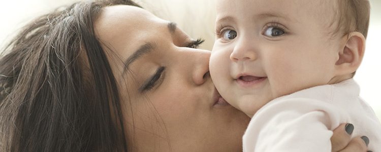 Mother holding and kissing a baby on the cheek