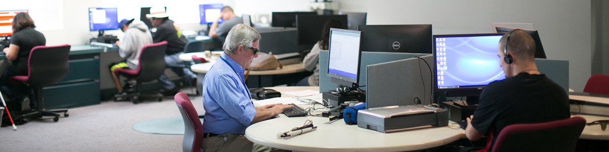 Dos personas usan computadoras en el laboratorio de capacitación en tecnología de asistencia de Wayfinder en Los Ángeles