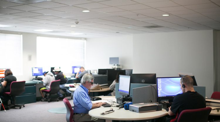 Dos personas usan computadoras en el laboratorio de capacitación en tecnología de asistencia de Wayfinder en Los Ángeles