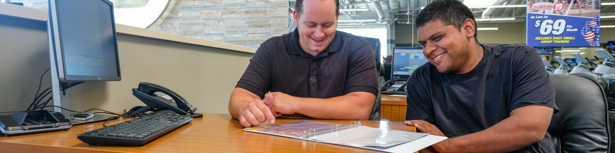 A young man sits at a desk with his employer