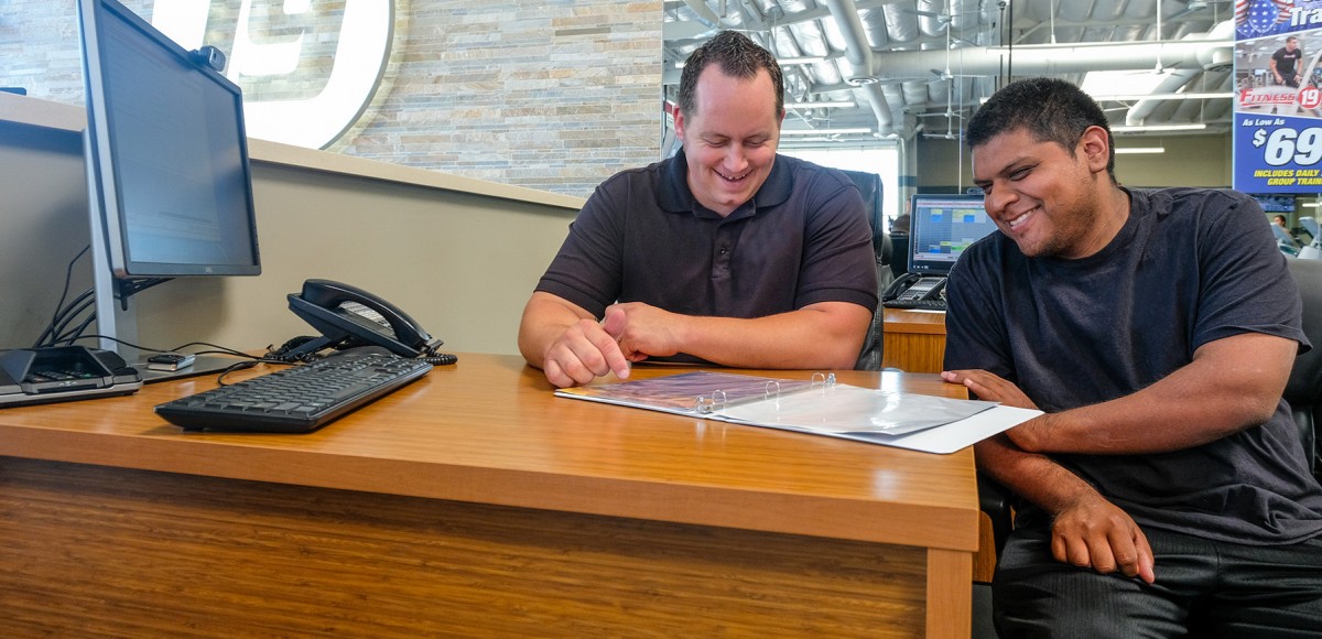 A young man sits at a desk with his employer