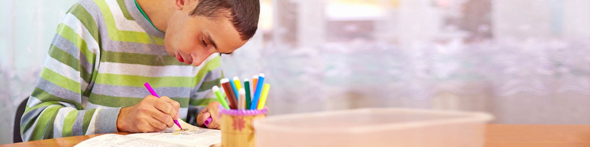 A young man colors at a table