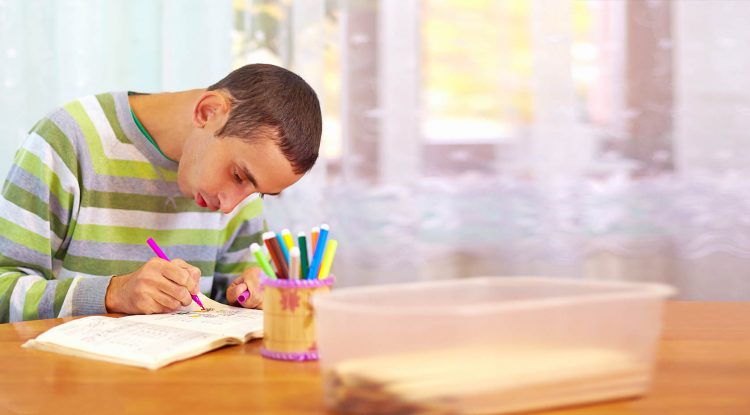 A young man colors at a table