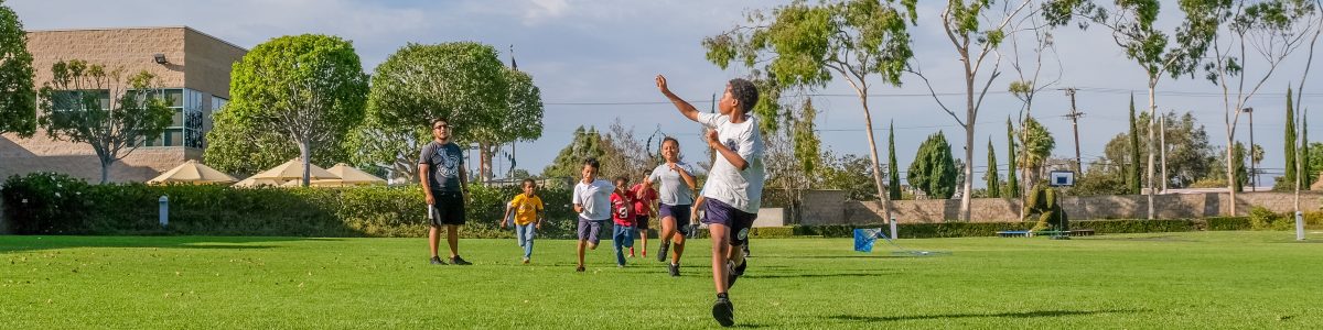 A young boy runs with a kite, with a group of children behind him