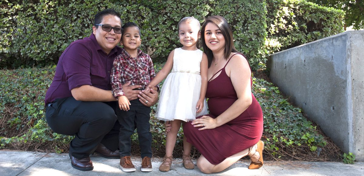 A young couple kneels next to their toddlers