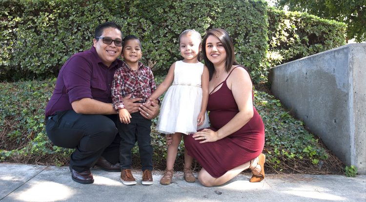 A young couple kneels next to their toddlers