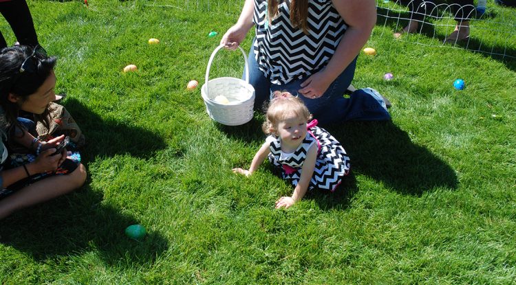 Baby Mackenzie crawls in the grass during a beeper egg hunt