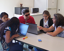 Teens who are visually impaired work on laptops with an instructor