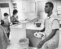 A young man holds a plate of food in Junior Blind's teaching kitchen