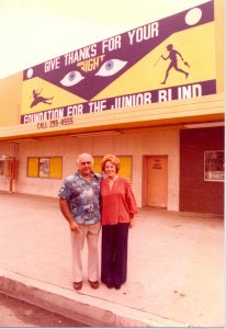 Gil and Vera Brown stand in front of a sign advertising the Foundation for the Junior Blind