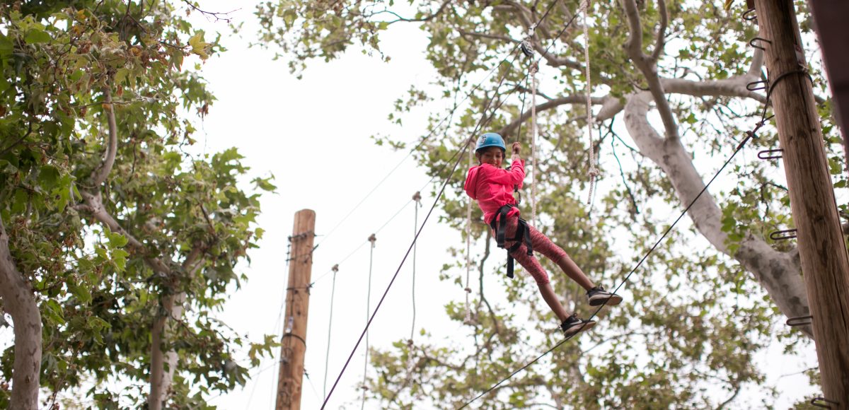 Camper doing ropes course up in the trees