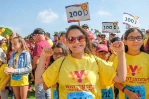 girl raising her arms and smiling at wayfinder paralympics