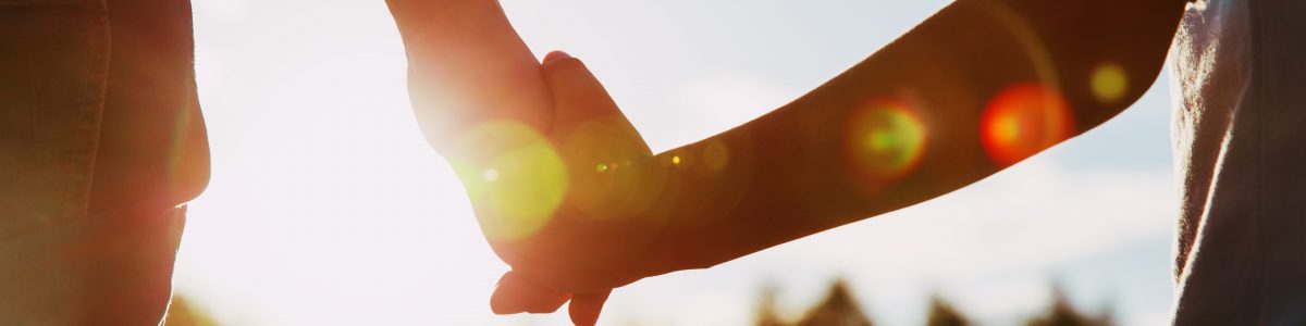 silhouette of parent and child holding hands at sunset