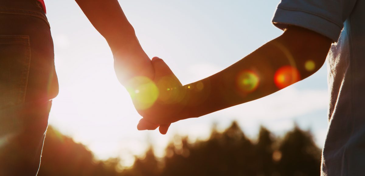 silhouette of parent and child holding hands at sunset