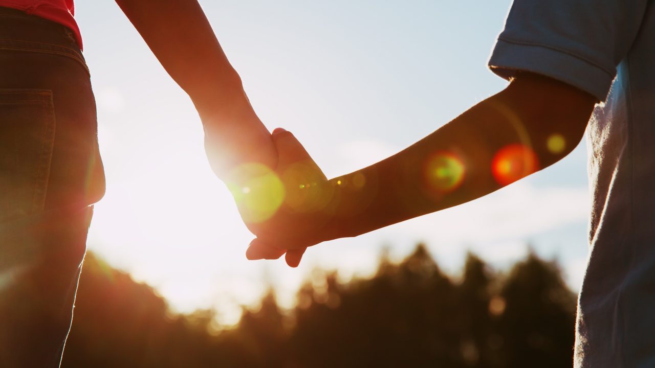 silhouette of parent and child holding hands at sunset