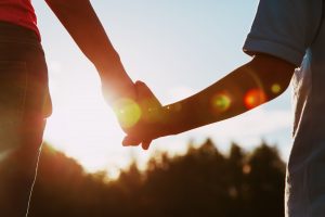 silhouette of parent and child holding hands at sunset
