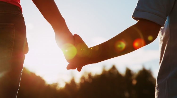 silhouette of parent and child holding hands at sunset