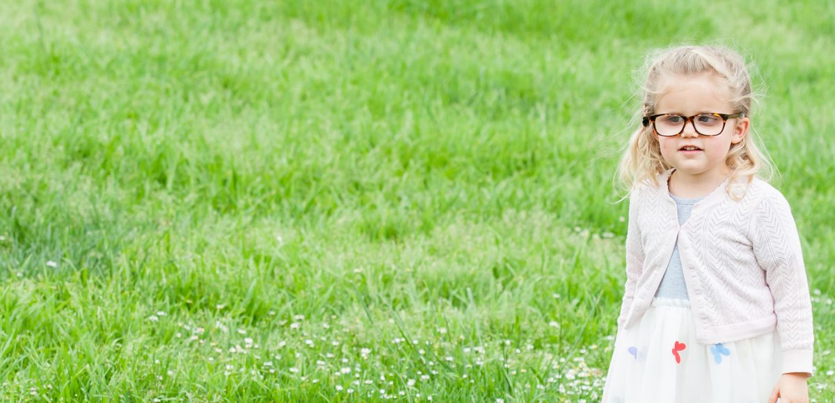 Smiling little girl wearing glasses and holding white cane