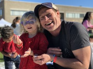 father and daughter play with snow