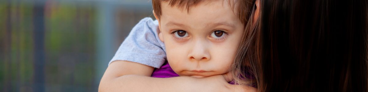 Little boy looks at camera while woman holds him