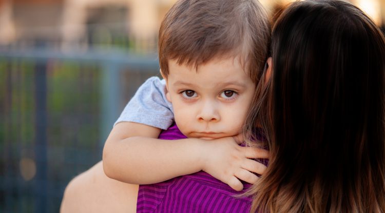 Little boy looks at camera while woman holds him