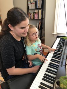female adult and little girl with glasses play piano