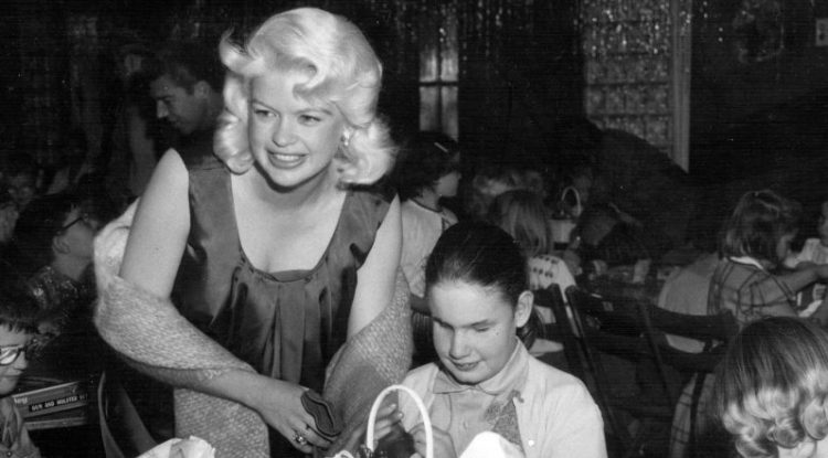 old photograph of blond actress smiling with child with visual impairment