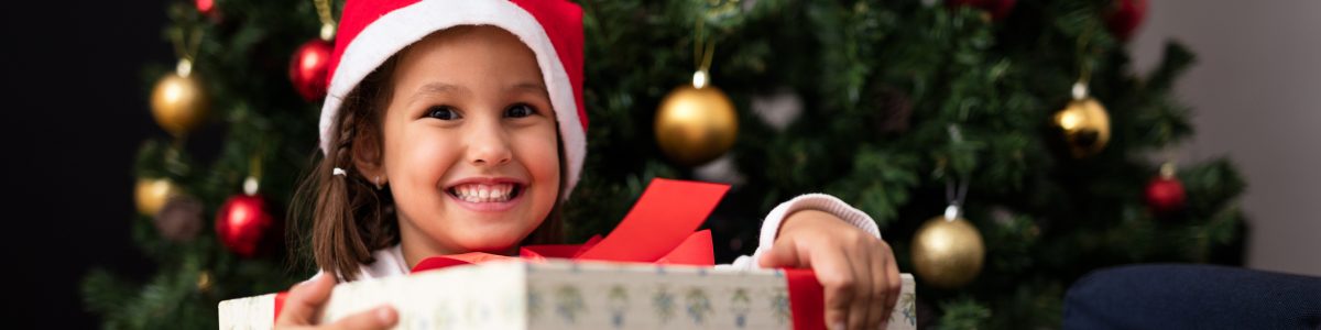 little girl with big gift under holiday tree