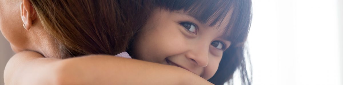 little girl embracing woman