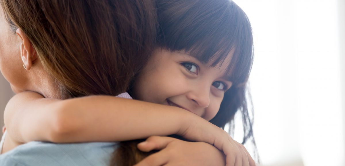 little girl embracing woman