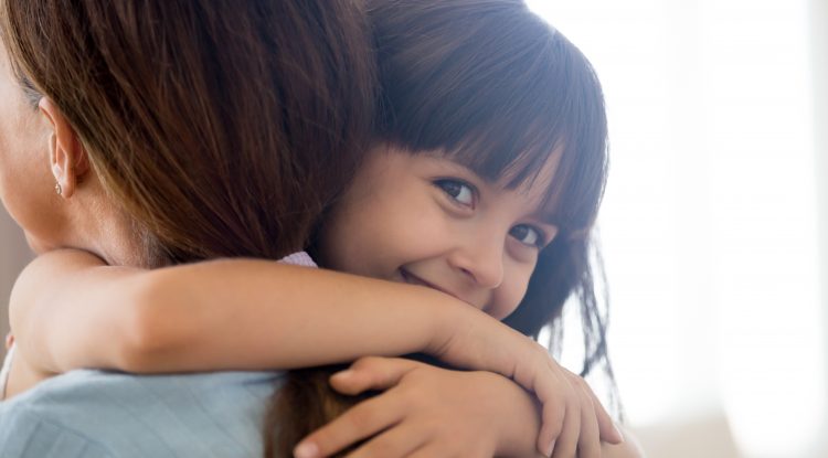 little girl embracing woman