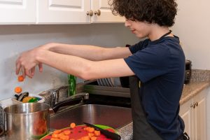 young boy cooking vegetables