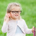 A young girl wearing glasses holds a beeping egg to his ear during the Beeper Egg Hunt