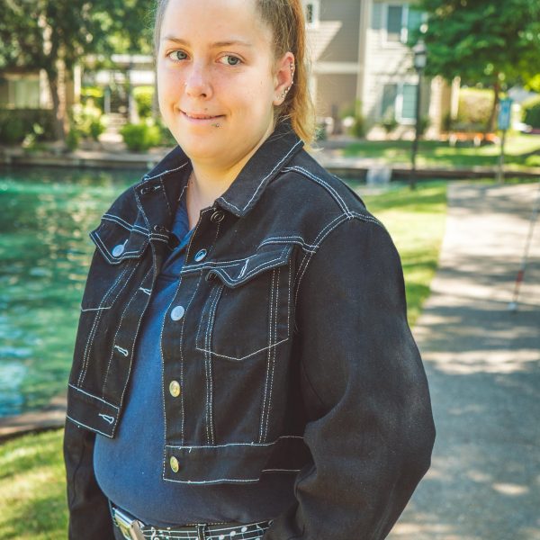 young woman standing near a fountain smiles into camera