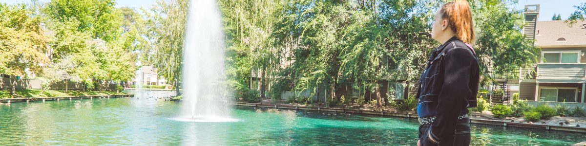 young woman standing on grass and looking at fountain