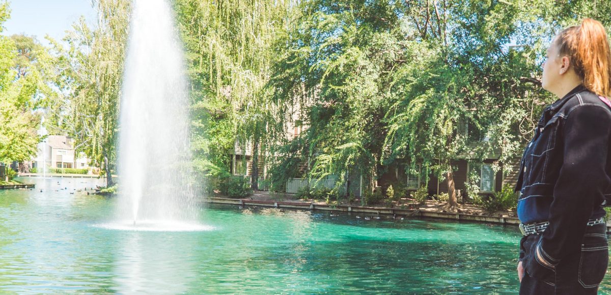 young woman standing on grass and looking at fountain