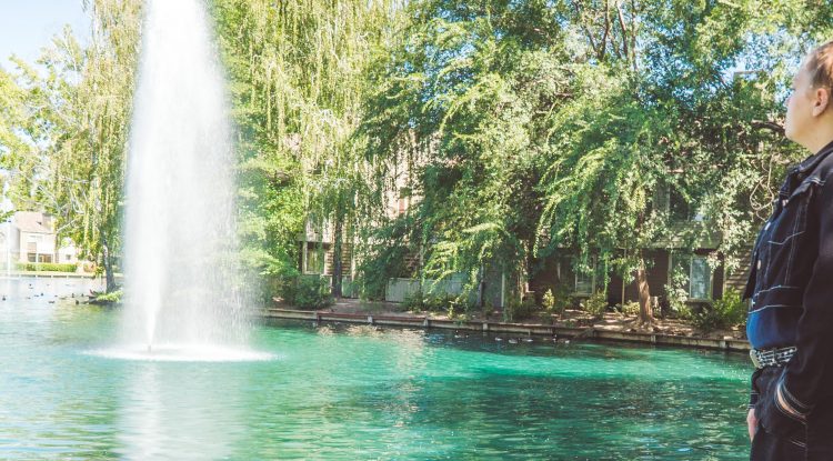 young woman standing on grass and looking at fountain