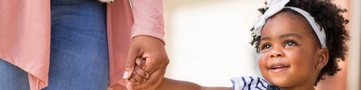 toddler smiling and holding adult's hand