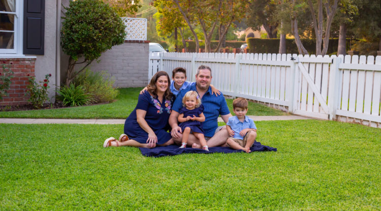 family of five sitting on grass