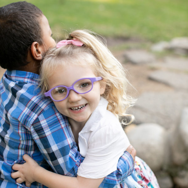 little girl with glasses hugging her brother