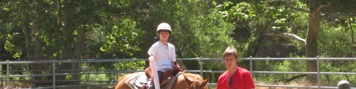 visually impaired camper on horse with a counselor standing next to them