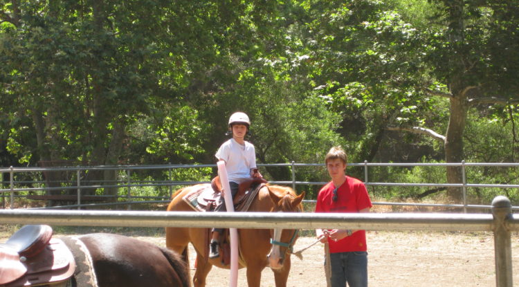 visually impaired camper on horse with a counselor standing next to them