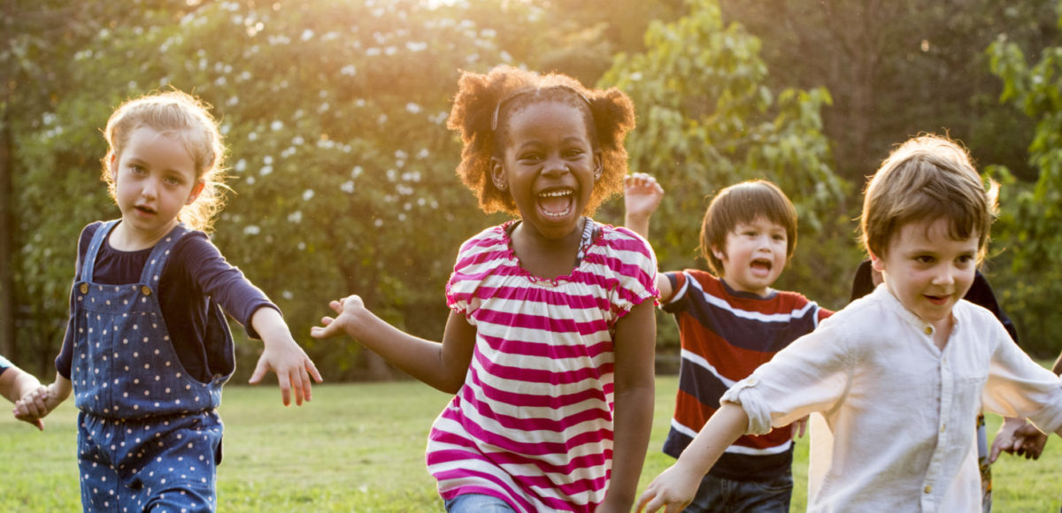 gorup of happy kids running on grass