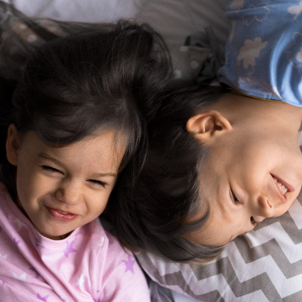 two young siblings laughing on bed
